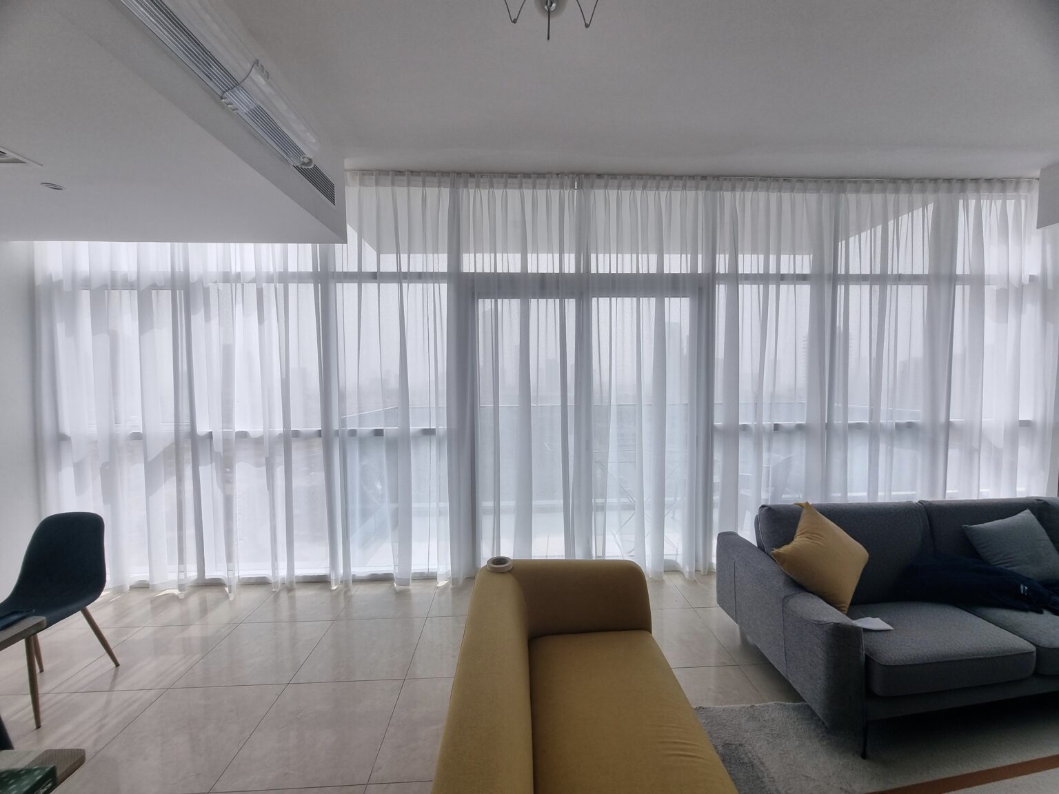 White chiffon sheer curtains in a Dubai high-rise living room with balcony view — soft daylight filtering by BCD
